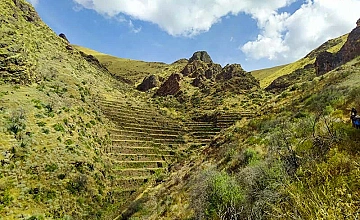 Subida por sendero empedrado rumbo a Huchuy Qosqo, Valle Sagrado de Cusco, entre laderas verdes